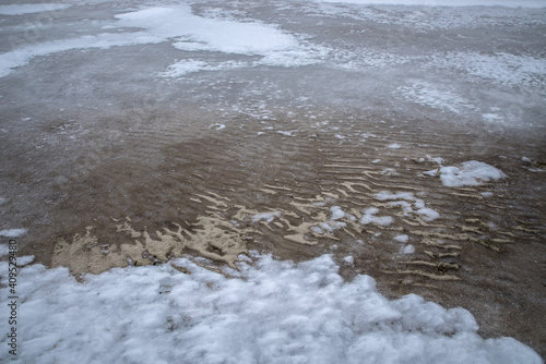 Texture of ice and frozen sand on the shore of the lake.