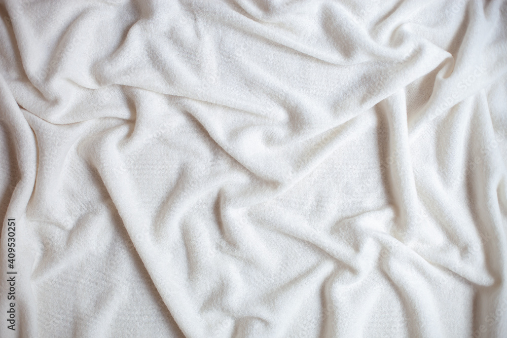 A white soft blanket in folds is spread out on the sofa.