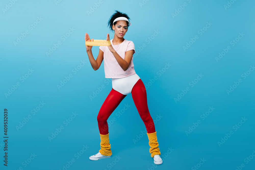 Graceful african girl in aerobics form training with expander. Full length view of shapely woman enjoying sport. Graceful african girl in aerobics form training with expander. Full length view of shapely woman enjoying sport.