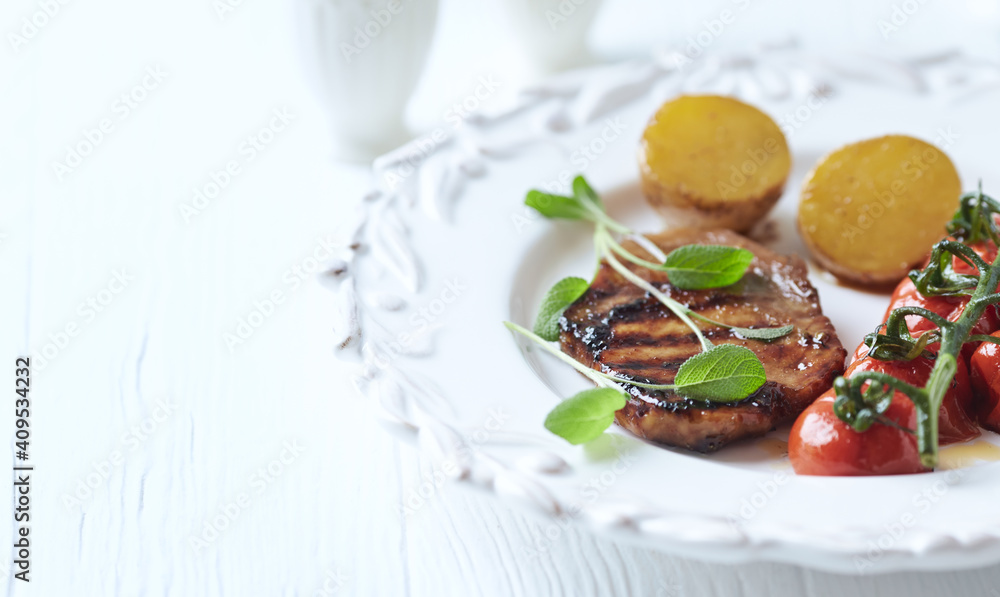 Grilled pork steak with vegetables. White wooden background. Close up. Copy space. 