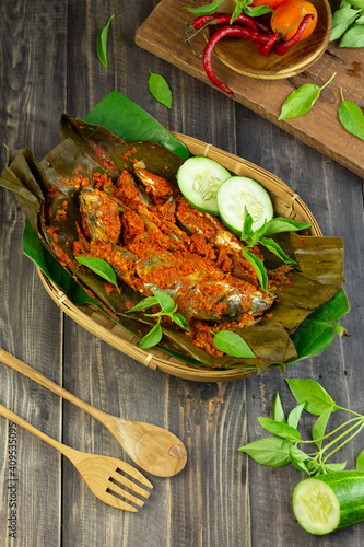 Pepes Ikan Layang or Pais Ikan or Steamed mackerel fish, typically Indonesian traditional food made from fish, spices, wrapped with banana leaves and steamed. Dark Wooden background.  photo