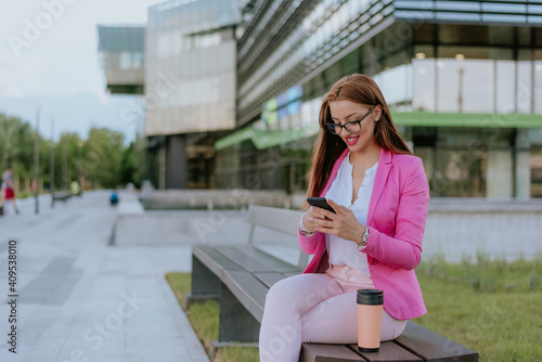 Beautiful woman sitting on bench and talking on mobile phone