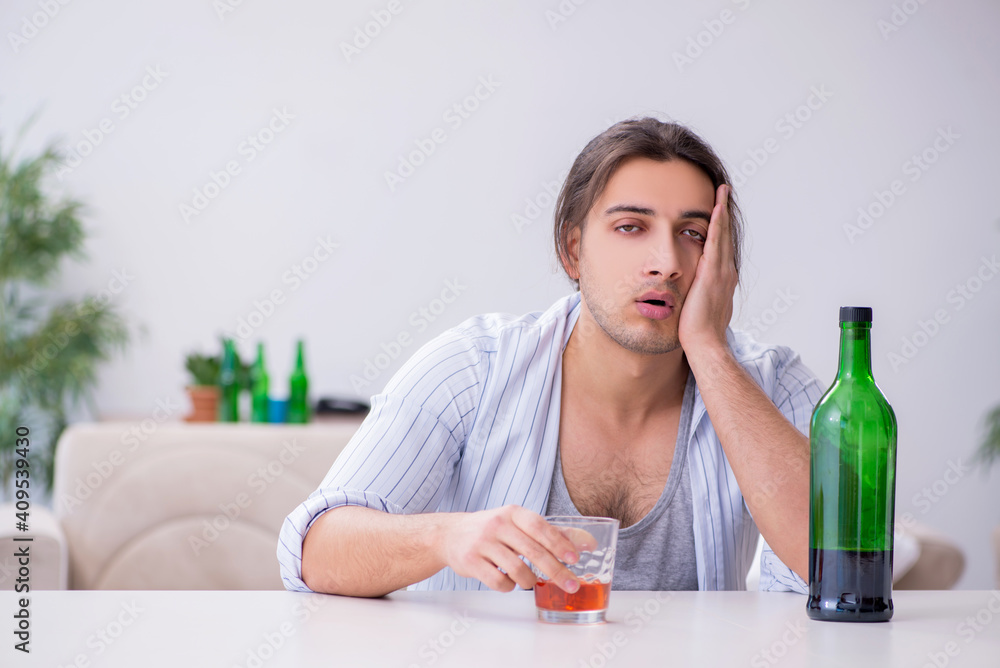 Young male alcoholic drinking whiskey at home Young male alcoholic drinking whiskey at home