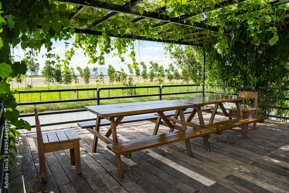 a deck with a long table and a view of nature on the side