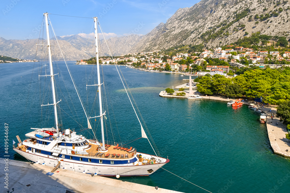 A sailing yacht is harbored on the Boka bay at the port of the European medieval city of Kotor, Montenegro.