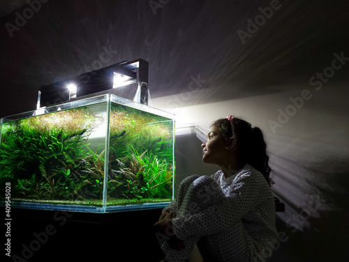 Girl admiring aquarium in his house at night