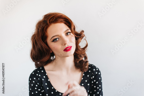 Interesed curly woman looking at camera. Front view of amazing ginger girl with red lips.