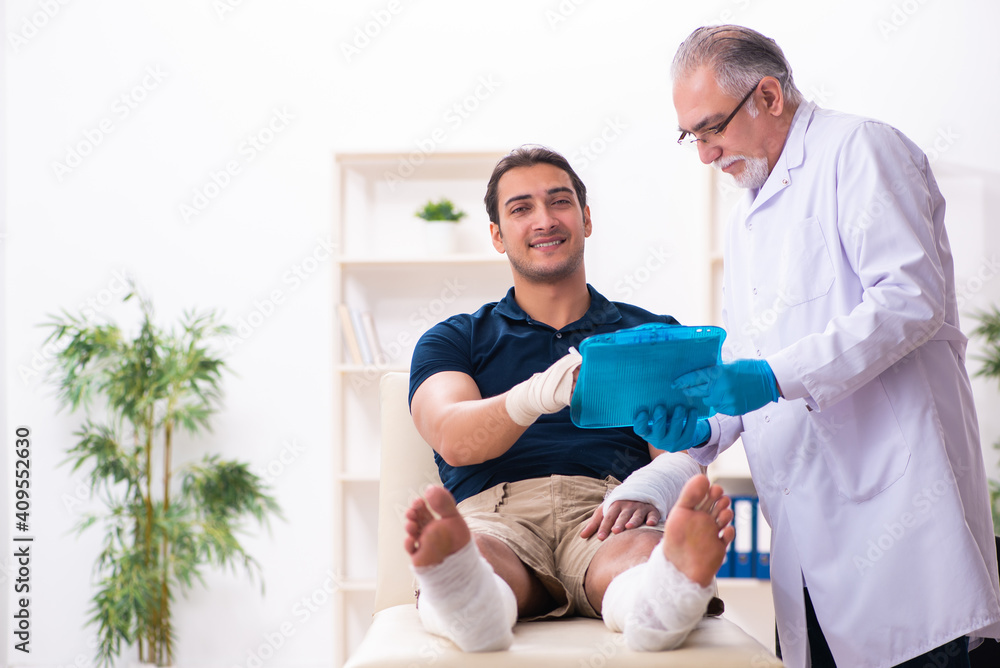 Obraz premium Young injured man visiting old doctor traumatologist