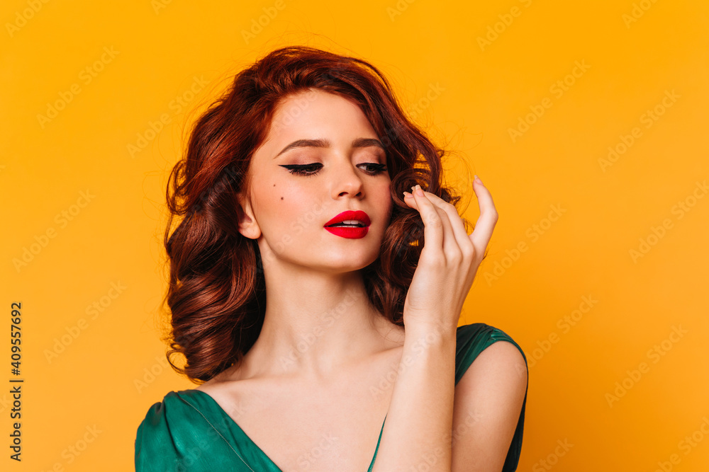 Pleasant female model posing on yellow background. Studio shot of romantic ginger girl in green dress. - obrazy, fototapety, plakaty 