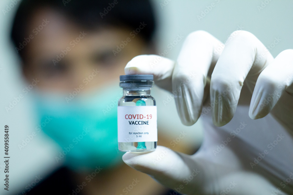 young doctor showing covid-19 vaccine bottle