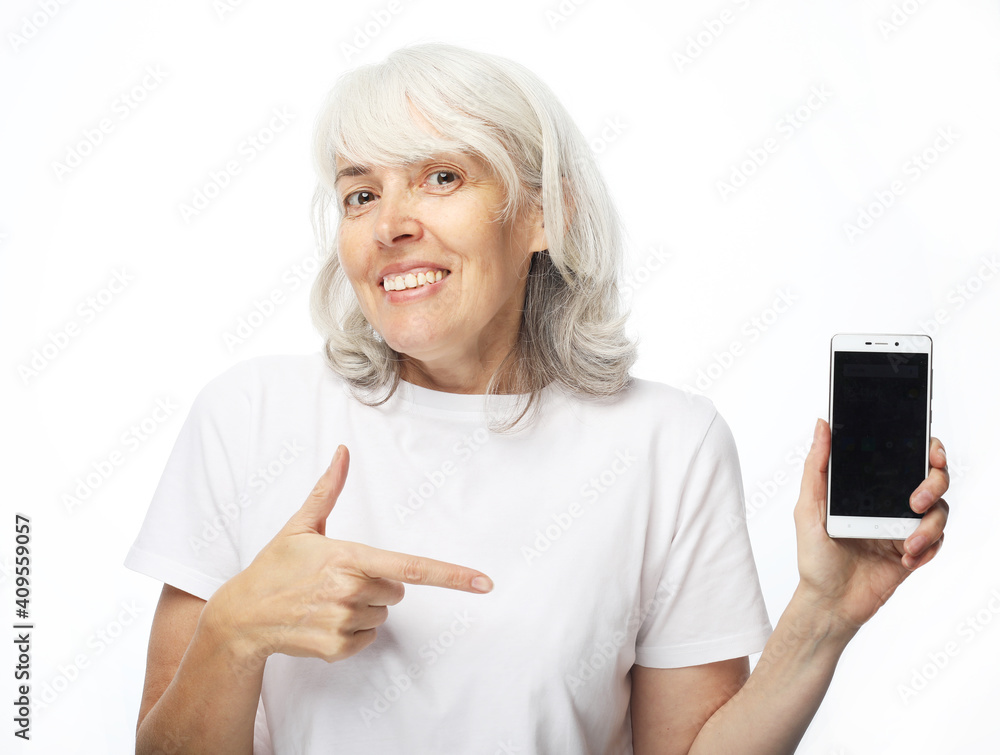 Elderly woman with white hair presents new smartphone over white background. Elderly woman with white hair presents new smartphone over white background.