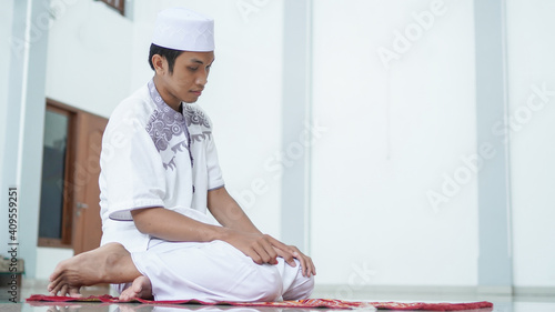 A portrait of an asian muslim man pray at mosque, the pray name is sholat, regards end of sholat