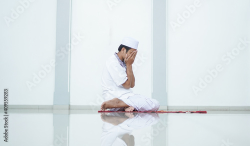 A portrait of an asian muslim man pray at mosque, the pray name is sholat, regards end of sholat
