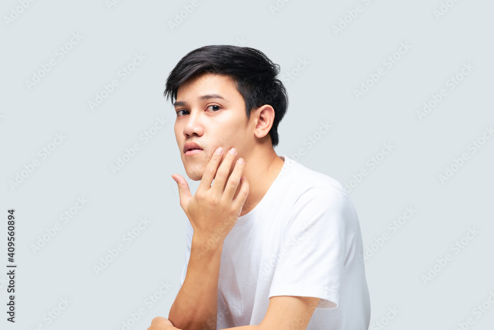 A young man using his hand touches cheeks for examining the health of his face. A young man using his hand touches cheeks for examining the health of his face.