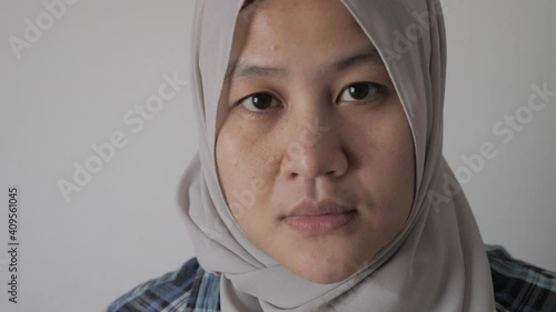 Asian muslim woman wearing hijab looking at camera with neutral expression, diverse people portrait