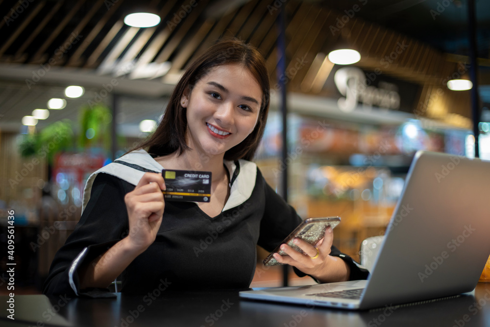 Beautiful Asian women holding credit card and mobile phone for shopping online.she smiling and happy Beautiful Asian women holding credit card and mobile phone for shopping online.she smiling and happy