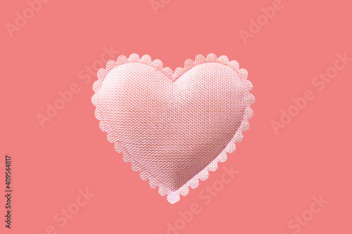 Gentle pink heart made of fabric isolated on lightcoral background.