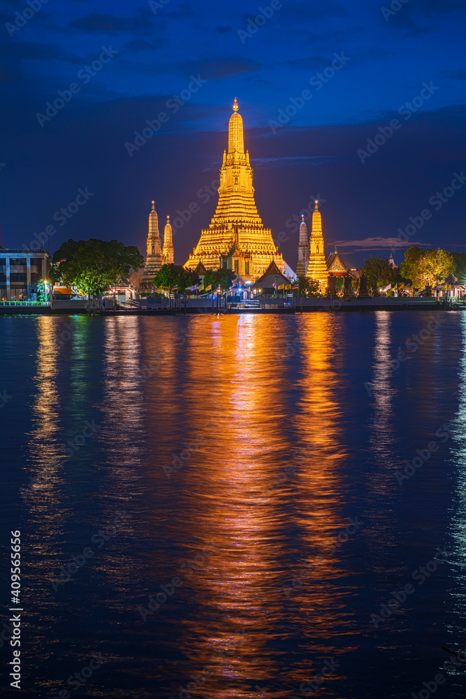 Fototapeta premium Beautiful vertical view of famous Wat Arun, the Buddhist temple of dawn, in the light of the blue hour after sunse