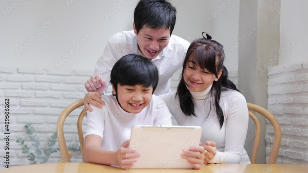 Happy Asian family talking video conference by computer together in living room , New normal lifestyle and activity technology, social distancing concept Happy Asian family talking video conference by computer together in living room , New normal lifestyle and activity technology, social distancing concept