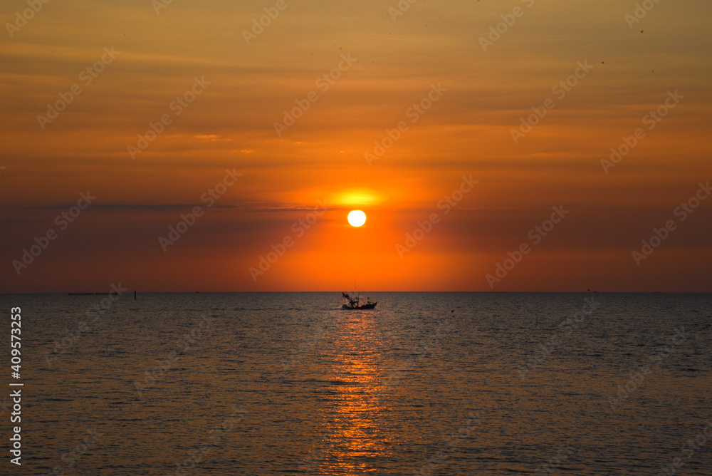 A beautiful sunset in the evening A fisherman's boat passed at Bang Saen Beach, Thailand.