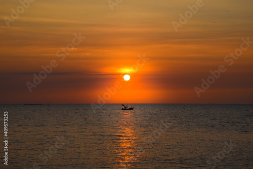 A beautiful sunset in the evening A fisherman's boat passed at Bang Saen Beach, Thailand.