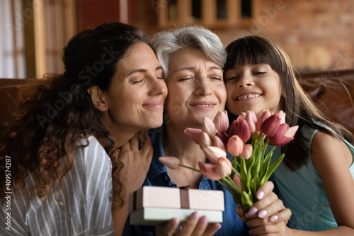 Stampa su tela Close up happy three generations of women celebrating event, touching cheeks, cu