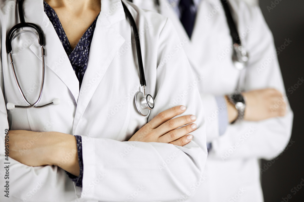 Group of modern doctors standing as a team with arms crossed in hospital office and ready to help patients. Medical help, insurance in health care, best disease treatment and medicine concept Group of modern doctors standing as a team with arms crossed in hospital office and ready to help patients. Medical help, insurance in health care, best disease treatment and medicine concept