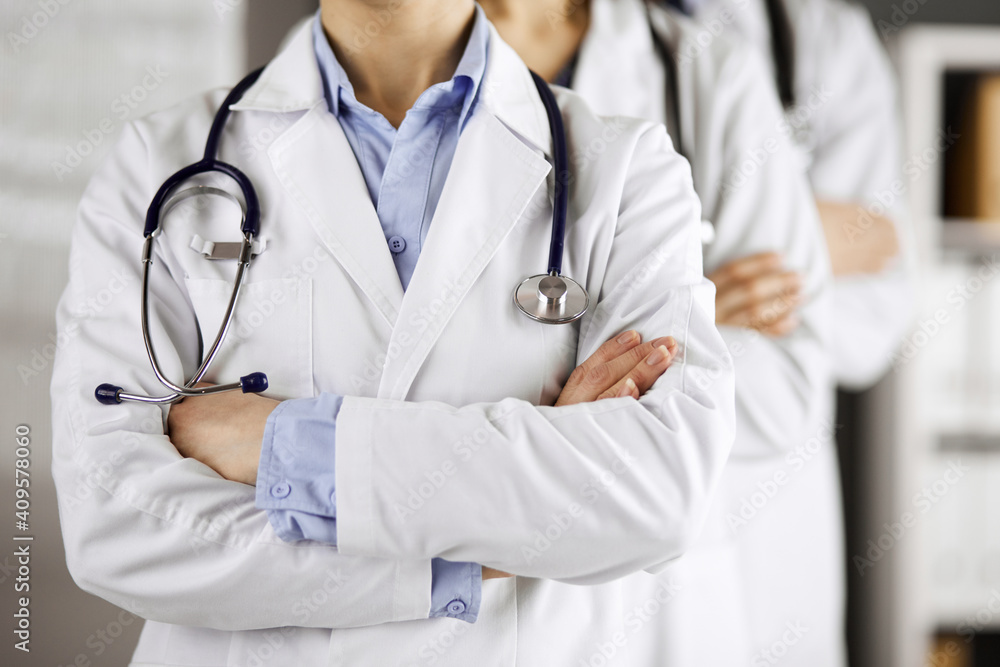 Group of modern doctors standing as a team with arms crossed in hospital office and ready to help patients. Medical help, insurance in health care, best disease treatment and medicine concept Group of modern doctors standing as a team with arms crossed in hospital office and ready to help patients. Medical help, insurance in health care, best disease treatment and medicine concept