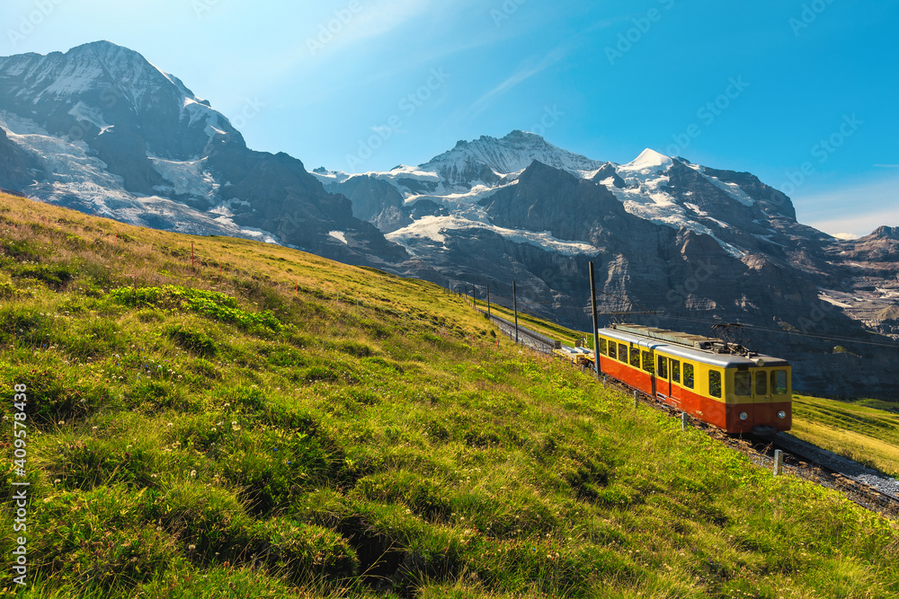 Electric retro tourist train and snowy mountains in background, Switzerland Electric retro tourist train and snowy mountains in background, Switzerland