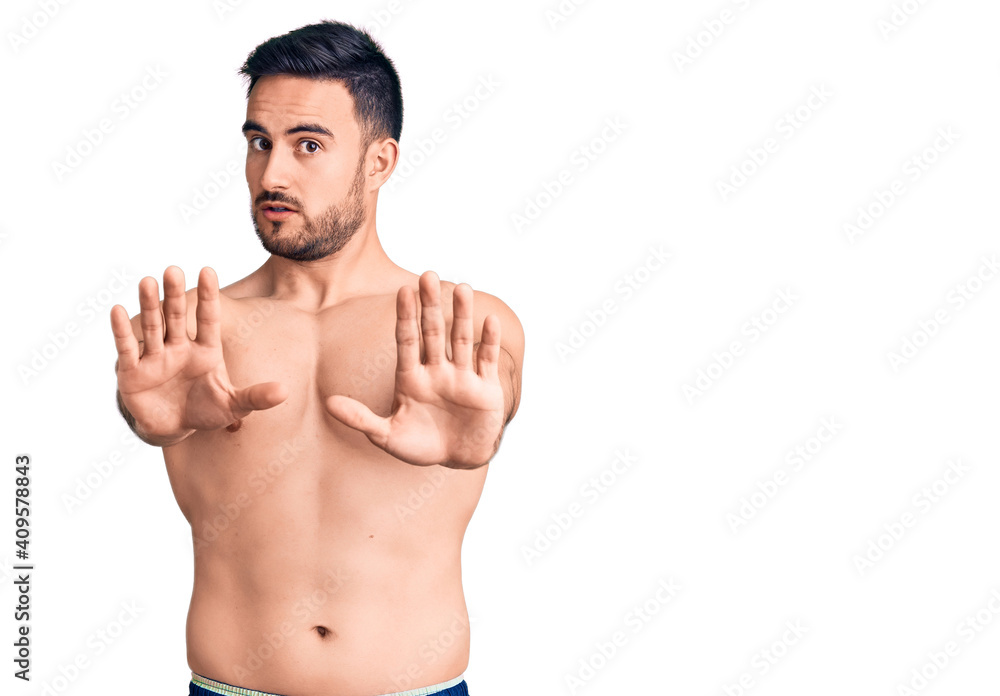 Fototapeta premium Young handsome man wearing swimwear doing stop gesture with hands palms, angry and frustration expression