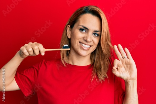 Wallpaper Mural Hispanic young woman holding toothbrush with toothpaste doing ok sign with fingers, smiling friendly gesturing excellent symbol Torontodigital.ca