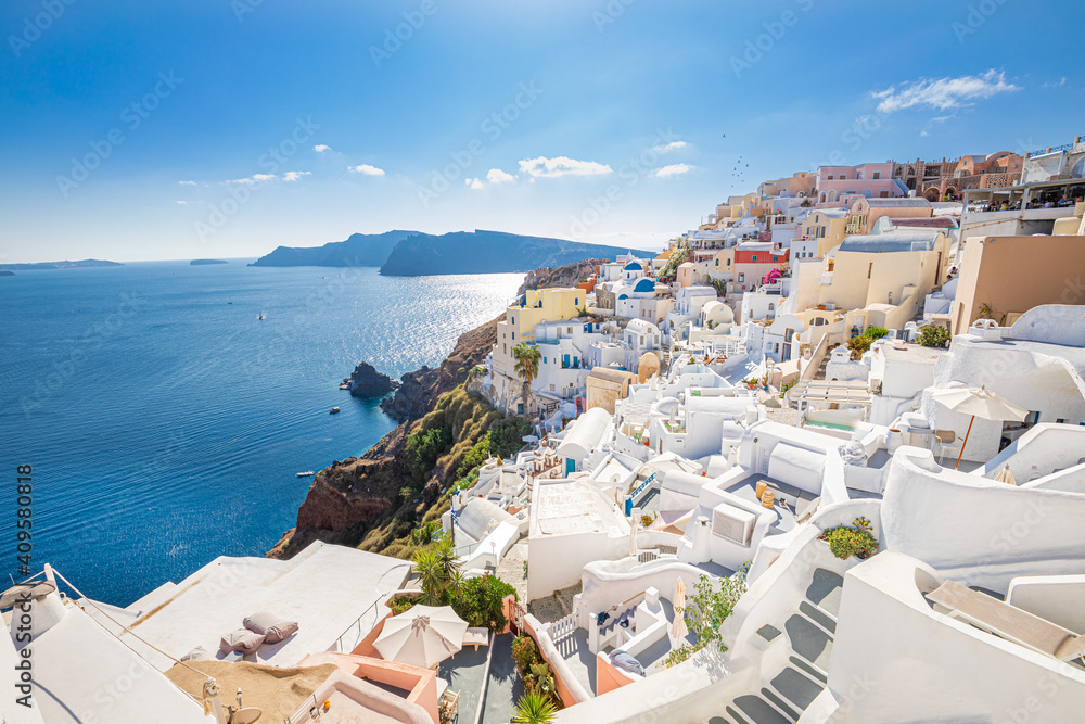 Beautiful Oia town on Santorini island, Greece. Traditional white architecture and Greek orthodox churches with blue domes over the Caldera. Luxury summer travel vacation destination, holiday scene