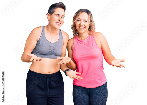 Couple of women wearing sportswear smiling cheerful with open arms as friendly welcome, positive and confident greetings © Krakenimages.com