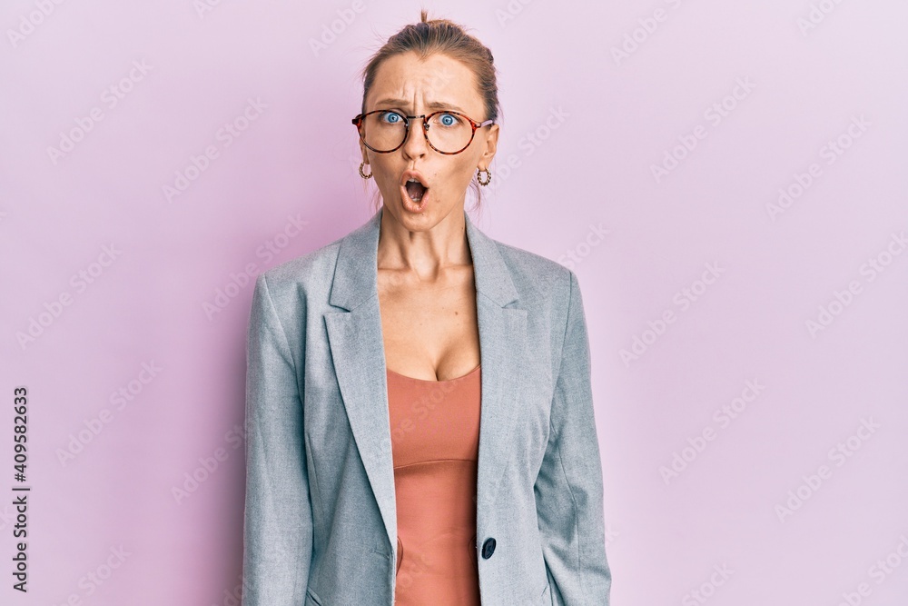 Beautiful caucasian woman wearing business jacket and glasses afraid and shocked with surprise expression, fear and excited face.