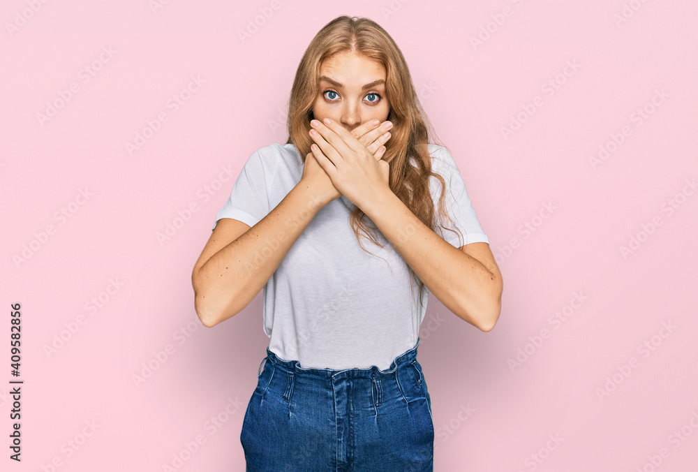 Young caucasian girl wearing casual white t shirt shocked covering mouth with hands for mistake. secret concept. Young caucasian girl wearing casual white t shirt shocked covering mouth with hands for mistake. secret concept.