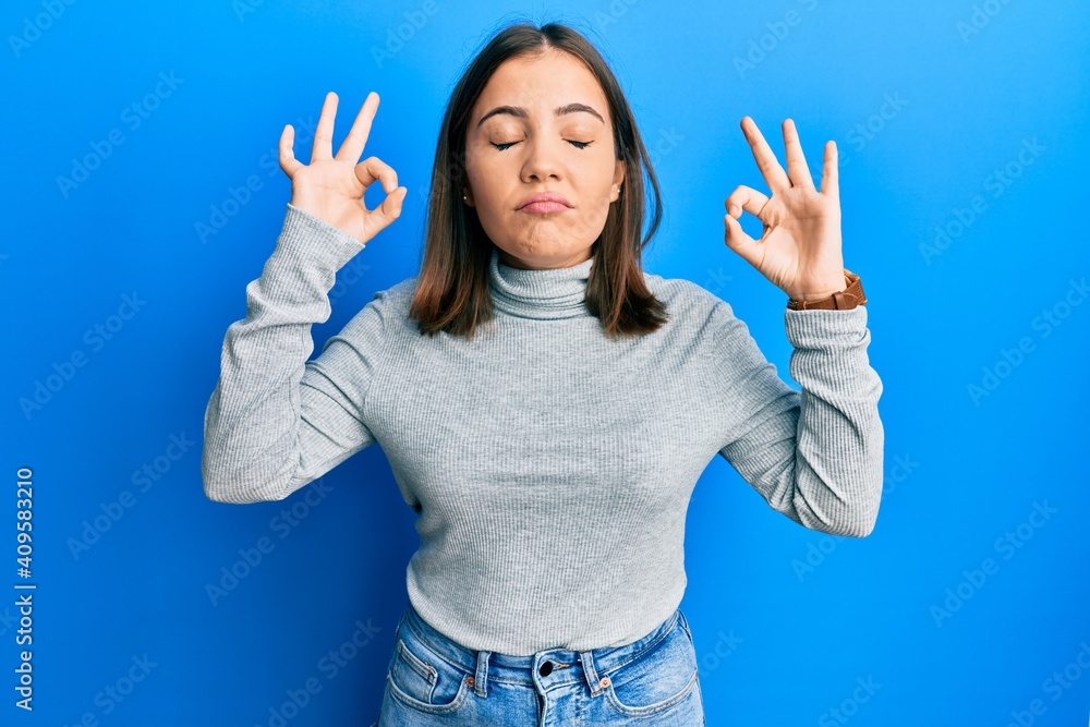 Young beautiful woman wearing casual turtleneck sweater relax and smiling with eyes closed doing meditation gesture with fingers. yoga concept. Young beautiful woman wearing casual turtleneck sweater relax and smiling with eyes closed doing meditation gesture with fingers. yoga concept.