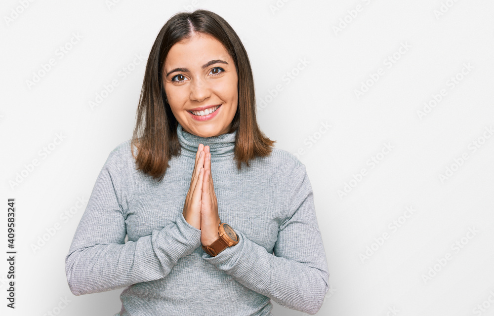 Young beautiful woman wearing casual turtleneck sweater praying with hands together asking for forgiveness smiling confident. Young beautiful woman wearing casual turtleneck sweater praying with hands together asking for forgiveness smiling confident.