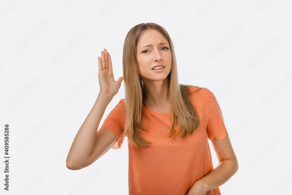 A hard of hearing young beautiful woman putting her hand to ear and listens. The concept of secrecy, eavesdropping A hard of hearing young beautiful woman putting her hand to ear and listens. The concept of secrecy, eavesdropping