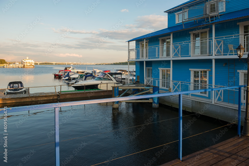 Boats and sailing boats are moored in the parking lot at the landing stage on the Volga river on a summer day