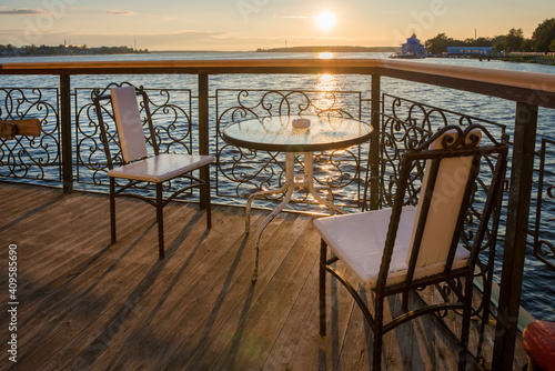 Table and chairs in a cafe on the river embankment on a summer evening at sunset