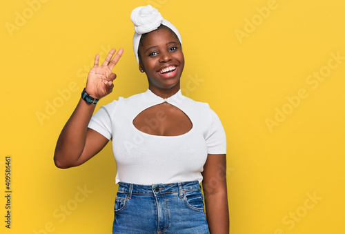 Young african woman with turban wearing hair turban over isolated background smiling positive doing ok sign with hand and fingers. successful expression.