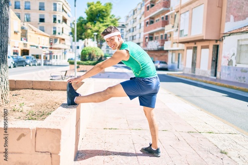 Young hispanic sportsman using earphones stretching at street of city © Krakenimages.com