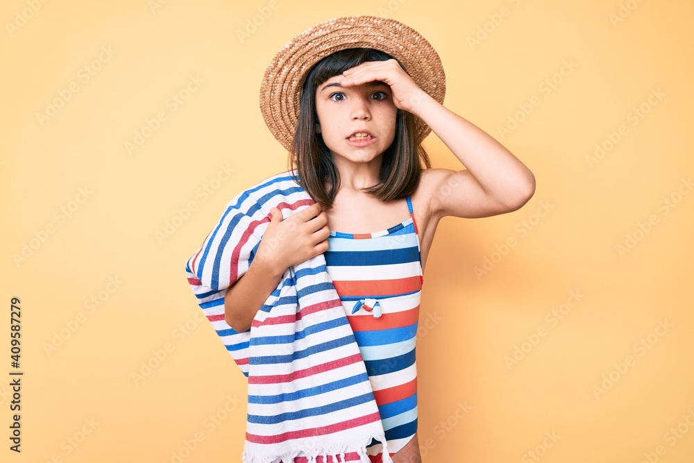 Young little girl with bang wearing swimsuit and summer hat holding towel stressed and frustrated with hand on head, surprised and angry face Young little girl with bang wearing swimsuit and summer hat holding towel stressed and frustrated with hand on head, surprised and angry face