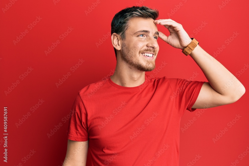 Handsome caucasian man wearing casual red tshirt smiling confident touching hair with hand up gesture, posing attractive and fashionable Handsome caucasian man wearing casual red tshirt smiling confident touching hair with hand up gesture, posing attractive and fashionable