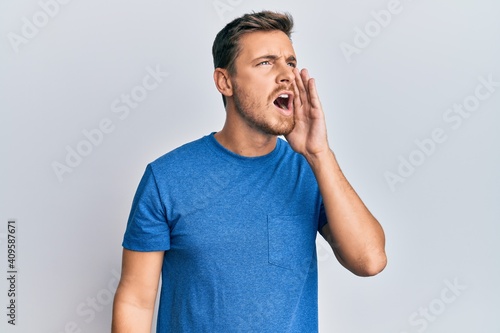 Handsome caucasian man wearing casual clothes shouting and screaming loud to side with hand on mouth. communication concept.
