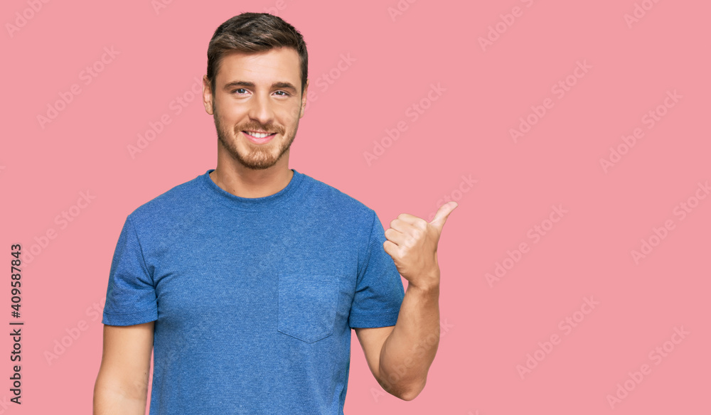 Handsome caucasian man wearing casual clothes smiling with happy face looking and pointing to the side with thumb up. Handsome caucasian man wearing casual clothes smiling with happy face looking and pointing to the side with thumb up.