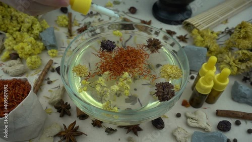Woman's hand puts ingredients to the glassware for preparation domestic cosmetics in slow motion. Alternative medicine, organic cosmetics, aromatherapy and natural care concept.