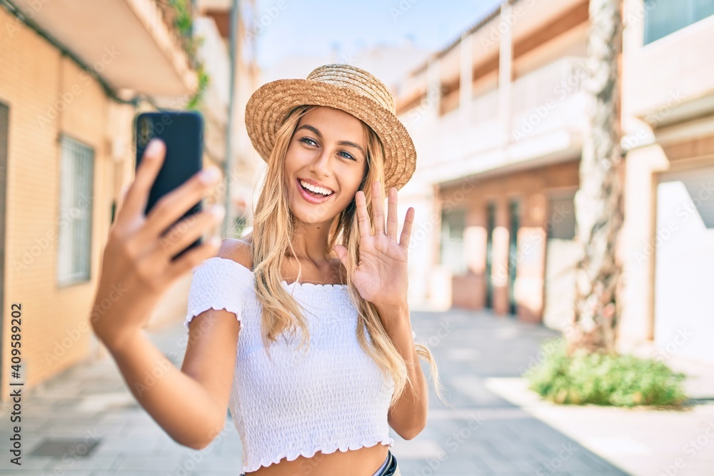 Young blonde tourist girl smiling happy doing video call using smartphone at the city.