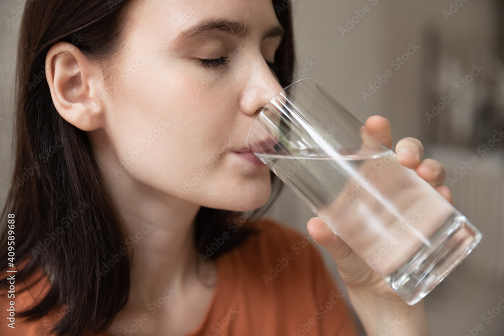 Close up thirsty beautiful woman with perfect smooth skin drinking enjoying cold pure mineral water, holding glass, preventing dehydration, healthy lifestyle habit, body balance, refreshment Close up thirsty beautiful woman with perfect smooth skin drinking enjoying cold pure mineral water, holding glass, preventing dehydration, healthy lifestyle habit, body balance, refreshment