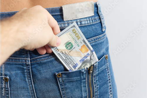 a hand pulls dollar bills out of the pocket of someone else's jeans. The concept of theft